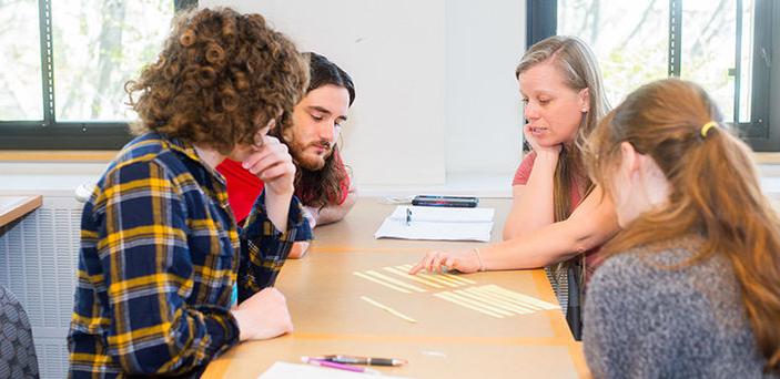 Professor 香农微冻 sits at a classroom table with 3 students explaining something with strips of paper laid out on the table